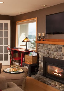 Stone fireplace with an orange fire glowing within and TV above the mantle..