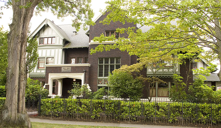 The stately, three-story Shafer Bailie Mansion sits amidst green foliage.