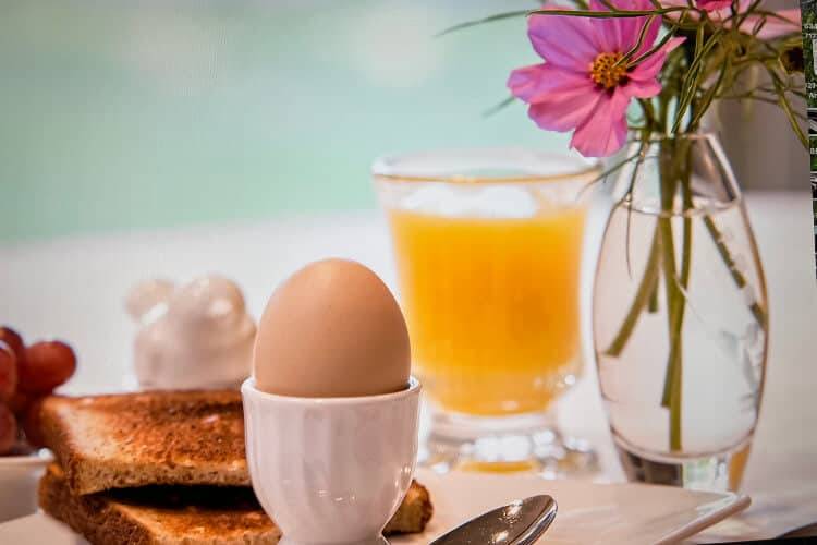 Healthy light breakfast consisting of toast, orange juice and red grapes. Flowers in clear vase.