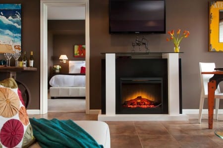 A sitting area in a suite at the Three Tree Point B&B with a white trimmed, black framed fireplace.