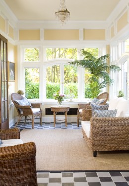 Room with large windows in the background and a table with chairs around it near the windows.