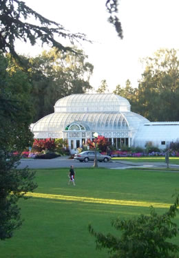 A person walking on the green lawn before a white Aboretum.