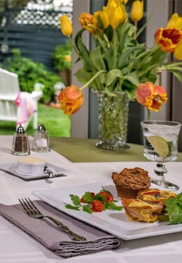 Breakfast table set with breakfast plate, glassware, orange tulips.