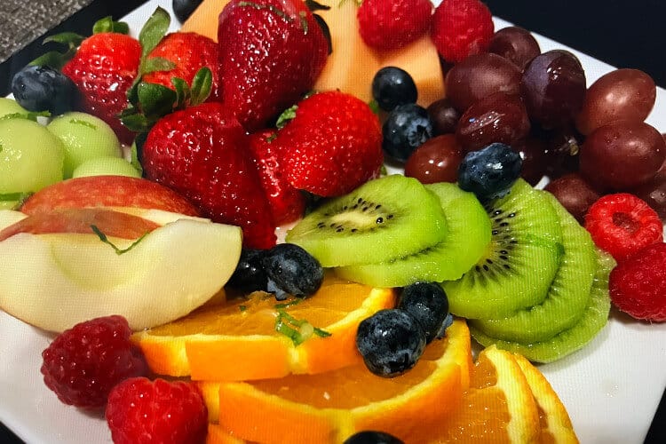 White plate holding variety of sliced fresh fruits