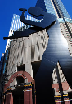 A gray steel sculpture of a worker with a hammer stands before a museum in Seattle.