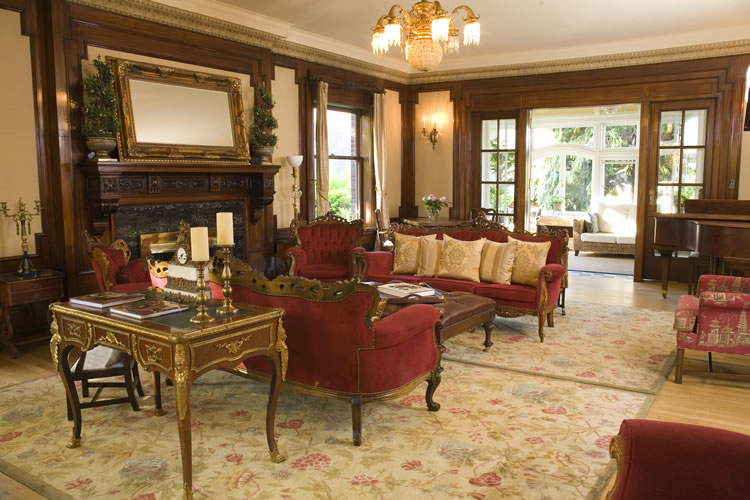 Red upholstered couches with white throw pillows rest on beige carpeting in a sitting room.
