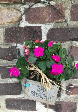 Basket with pink flowers hanging on brick wall with Bed & Breakfast sign